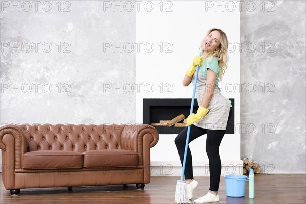 Playful woman dancing with mop near bucket detergent bottle
