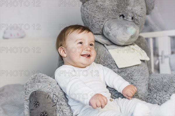 Cute blonde baby white bed with teddy bear