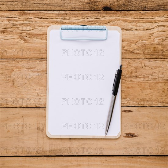 Blank paper clipboard with ballpoint pen wooden desk