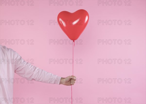 Person holding red balloon with twist