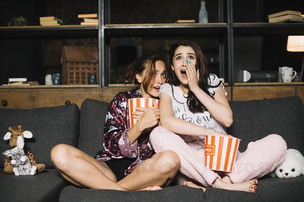 Portrait two frightened female friends watching television