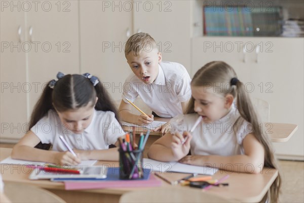 Boy peeping into notebooks girls