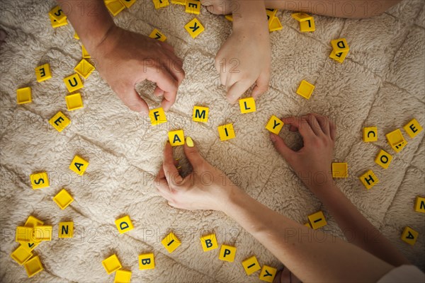 Hands playing scrabble game carpet home