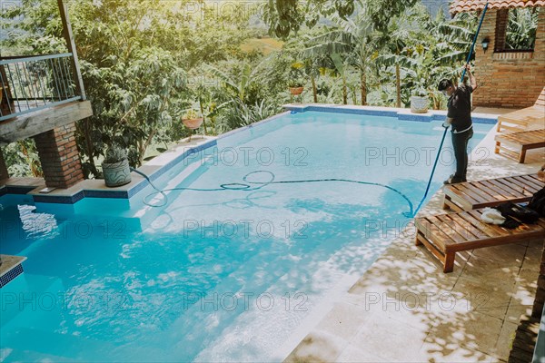 Pool maintenance and cleaning with vacuum suction hose. Worker cleaning a beautiful swimming pool with vacuum suction hose