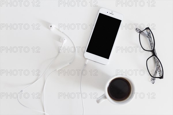 Overhead view cellphone with connected earphone coffee cup eyeglasses