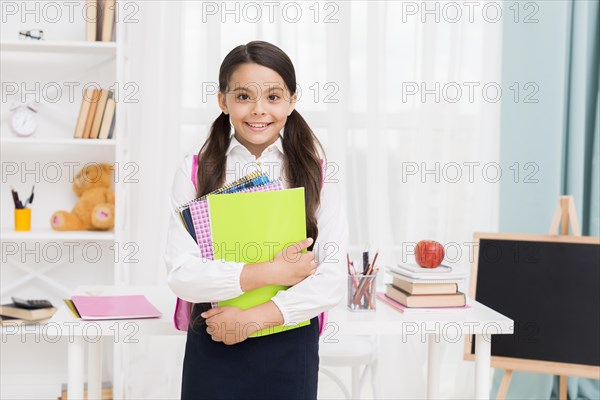 Cute schoolgirl uniform holding notepads classroom