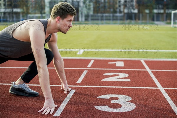 Young male athlete ready run taking position start line