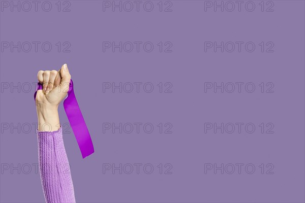 Woman s hand holding violet ribbon copy space