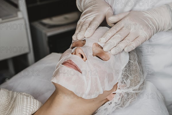 Young woman getting skin mask treatment spa