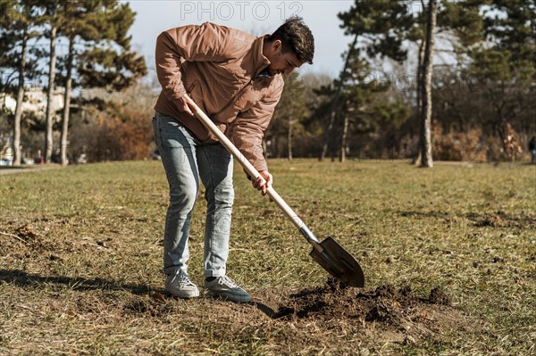 Side view man using shovel dig hole planting tree