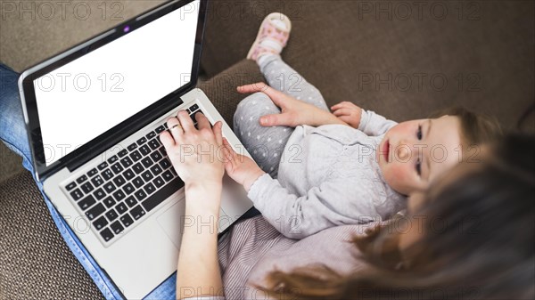 Elevated view woman with her daughter using laptop with blank white screen