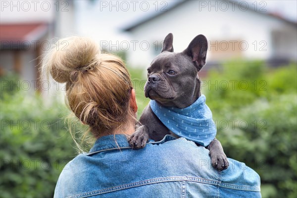 Woman holding French Bulldog dog over shoulder