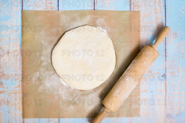 Wooden rolling pin flat dough parchment paper wooden table