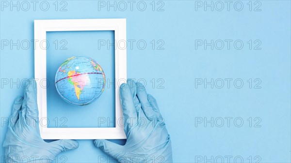 Top view hands with surgical gloves holding frame earth globe with copy space