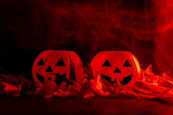 Halloween pumpkins on autumn leaves with smoke on a red background