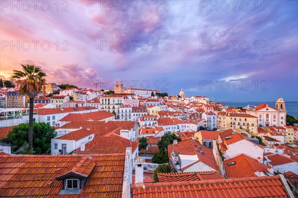 View of Lisbon famous view from Miradouro de Santa Luzia tourist viewpoint over Alfama old city district on sunset with dramatic overcast sky. Lisbon