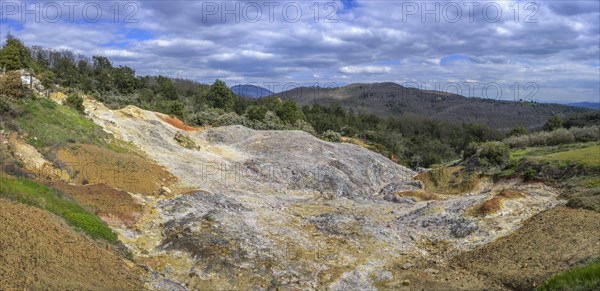 Colourful rubble deposits are surrounded by forest