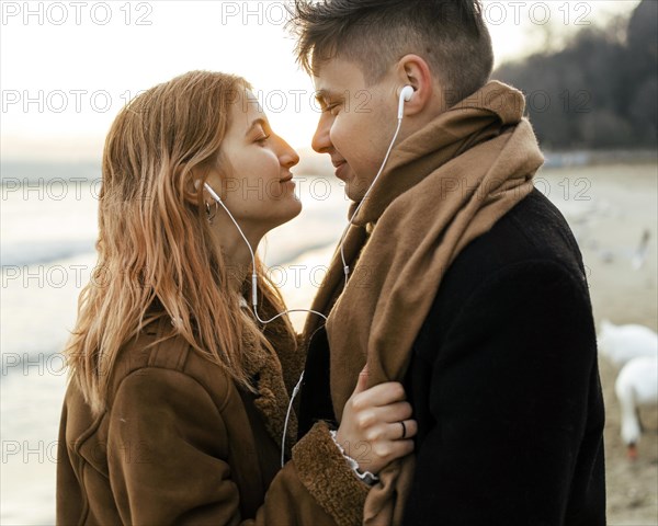 Couple listening music earphones beach winter