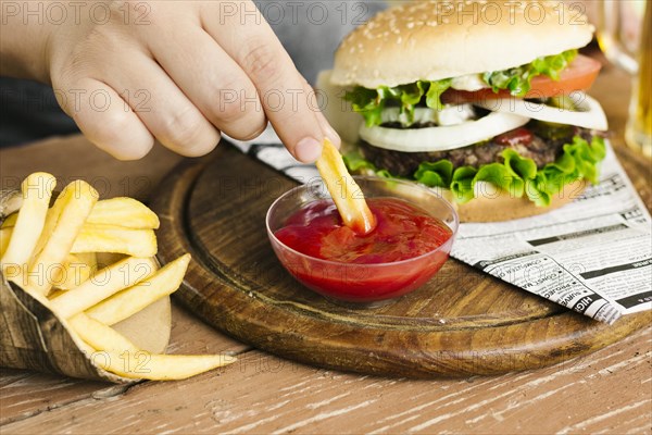 Hand dipping fries with burger