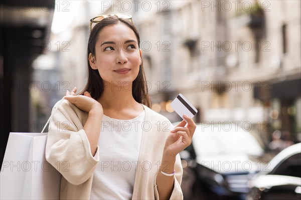 Woman outdoors holding credit card shopping bag