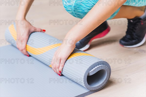 Close up female hand folding yoga mat