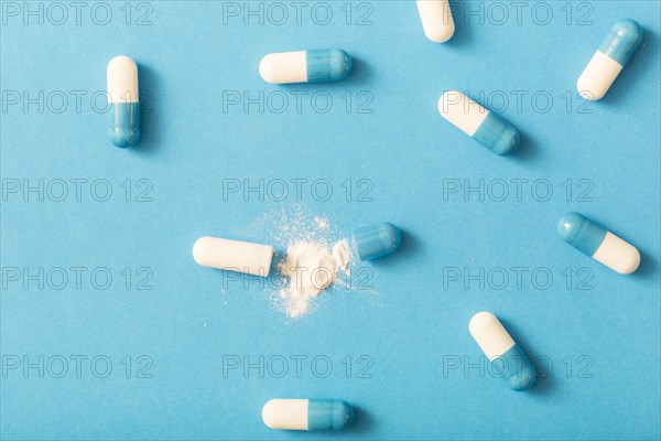 Split open capsule with white powder blue background