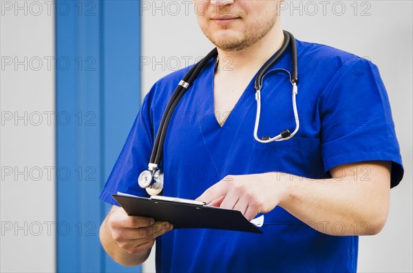 Portrait male doctor with stethoscope around his neck examining medical report