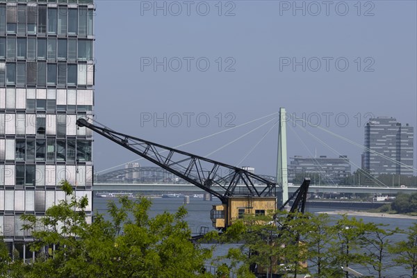 Old cargo crane in Cologne's Rheinauhafen in front of the Rhine and Severinsbruecke