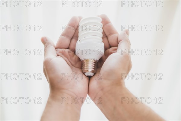 Close up hand holding compact fluorescent light bulb