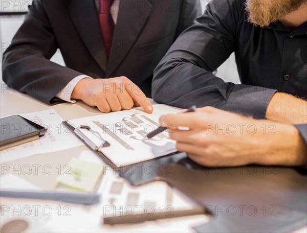 Close up two businessmen pointing business chart meeting