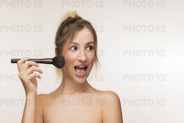 Happy woman holding makeup brush