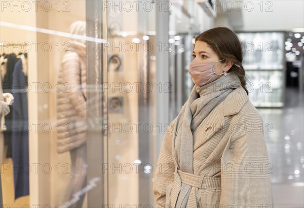 Side view woman with medical mask window shopping