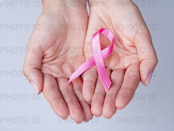 Close up hands holding pink ribbon