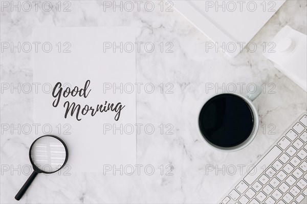 Magnifying glass good morning paper with coffee cup diary keyboard white marble desk