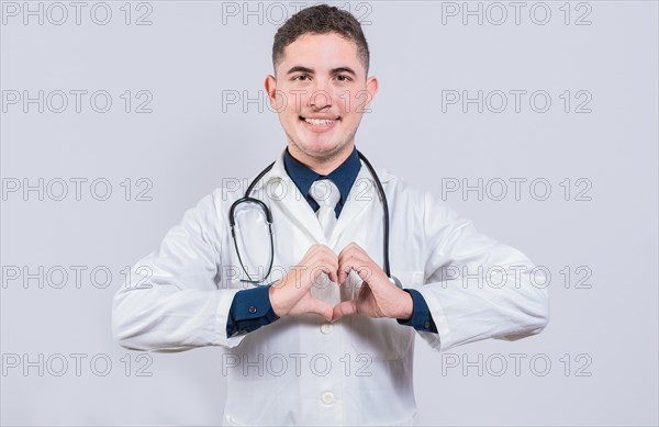 Friendly doctor making heart gesture with hands isolated. Young latin doctor making heart shape on isolated background