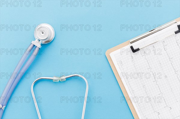 Overhead view stethoscope near ecg paper graph report blue backdrop