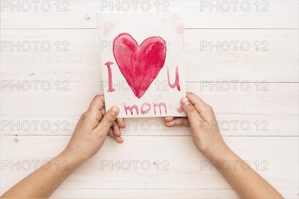 Person holding paper with i love you mom inscription
