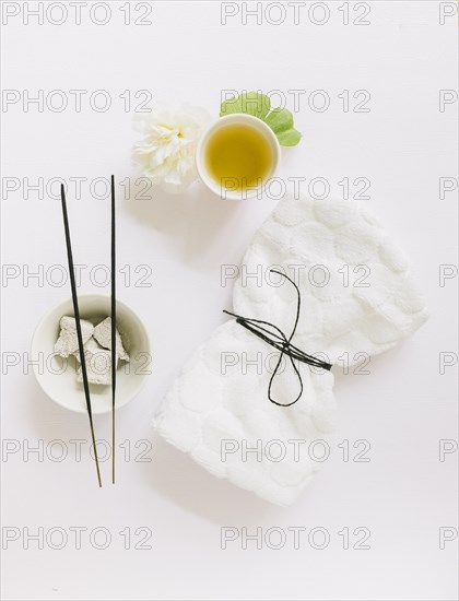Top view incense stick pumice stone flower gingko leaf oil tied napkin white background