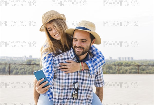 Woman using cellphone while having piggyback her boyfriend s back