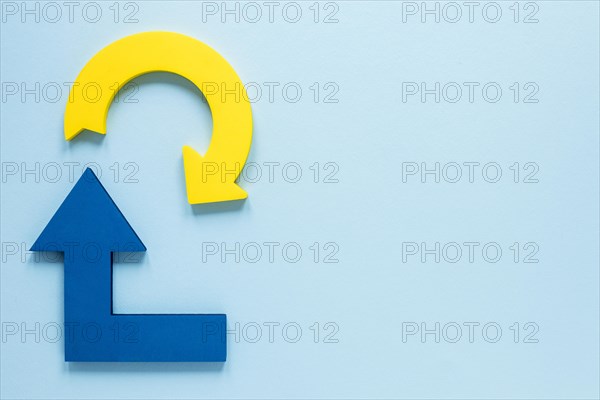 Flat lay blue yellow arrows blue background with copy space