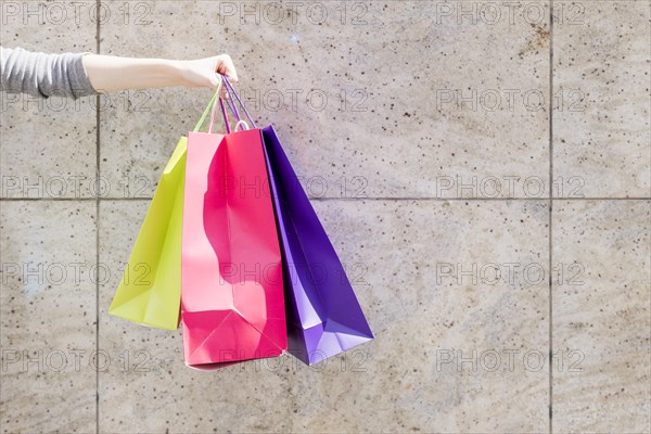 Close up woman s hand with colorful shopping bags front wall