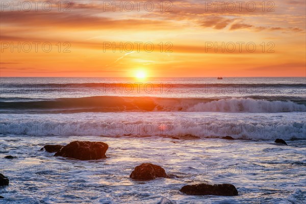 Atlantic ocean sunset with waves and rocks at Costa da Caparica