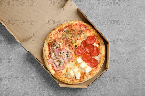 Top view of classic pizza four seasons in takeaway cardboard box