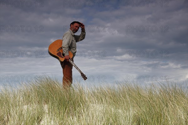 Man with guitar in the dunes
