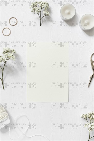 Blank card surrounded with gypsophila wedding rings string scissor white background