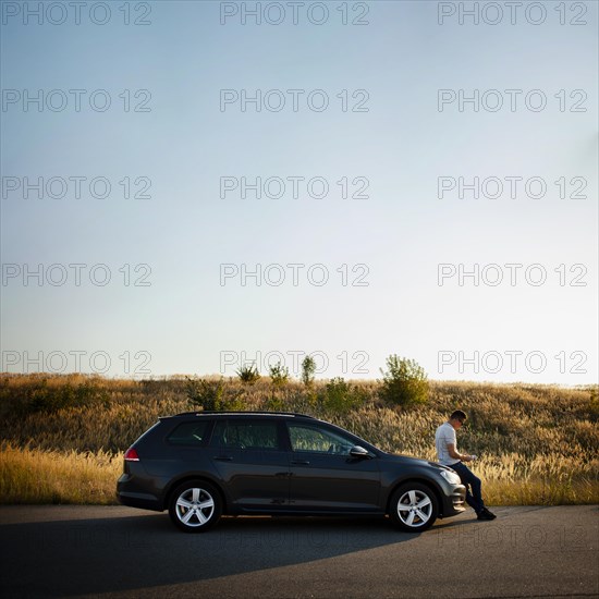 Man sitting car hood