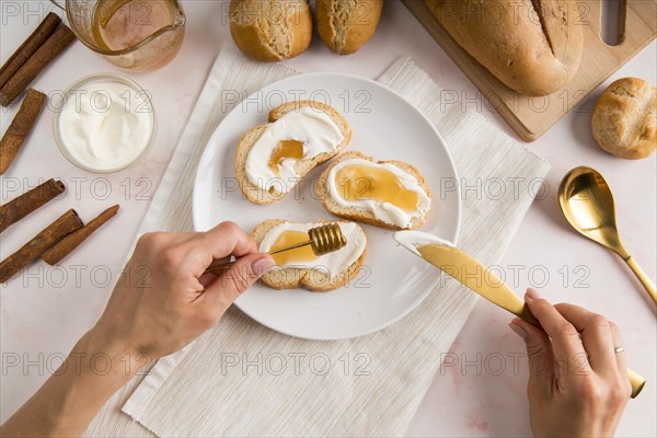 Flat lay woman spreading cream cheese bread