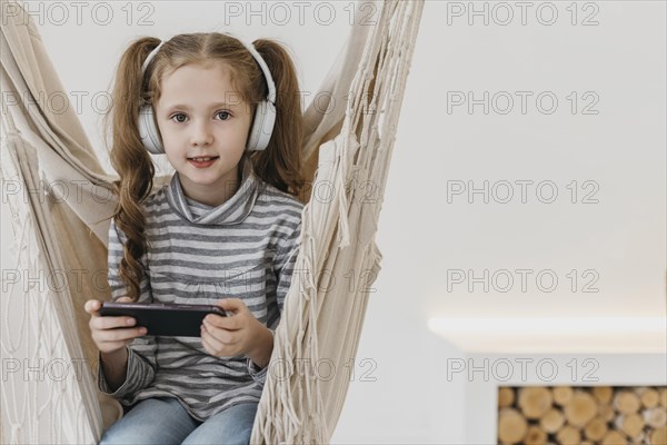 Girl holding mobile phone wearing headphones