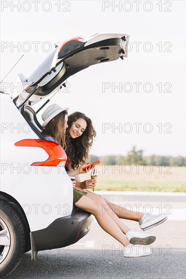 Women sitting trunk white car