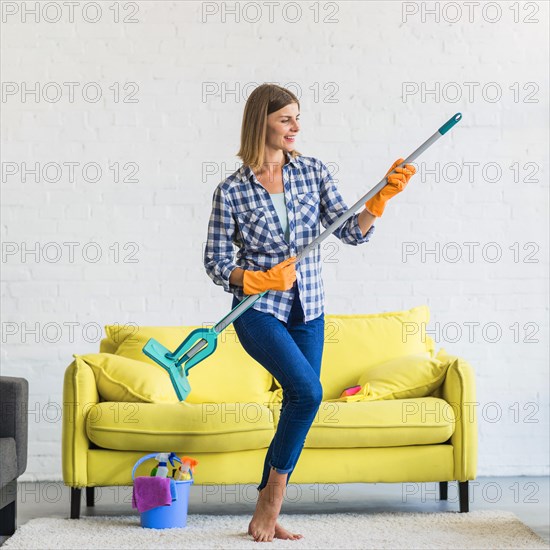 Smiling young woman acting like playing guitar living room